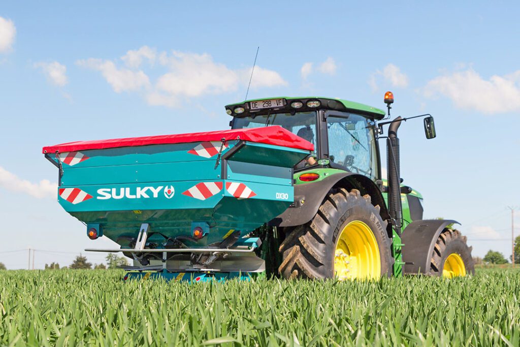 Tractor spreading fertiliser in crop field